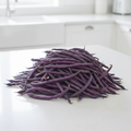 Abundance of long slender deep purple King of the Blues climbing bean pods piled on a light kitchen bench