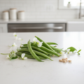 Fresh Blue Lake bush beans with white flowers and bean seeds on a light kitchen bench