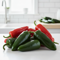 Large jalapeño Megatron chillies in green and red on a bright airy kitchen bench