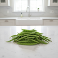 Fresh Short Swiss beans, short wide flat green pods piled on a white kitchen bench