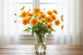 Cosmos sulphureus Orange — vivid golden-orange single blooms with broad lobed leaves and rounded buds in a clear glass vase in front of a bright window