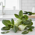 Fresh pak choi with thick crisp white stems and glossy dark green leaves on a bright airy kitchen bench